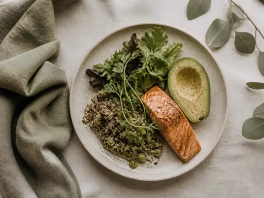 A balanced plate of salmon, greens, avocado and quinoa on linen