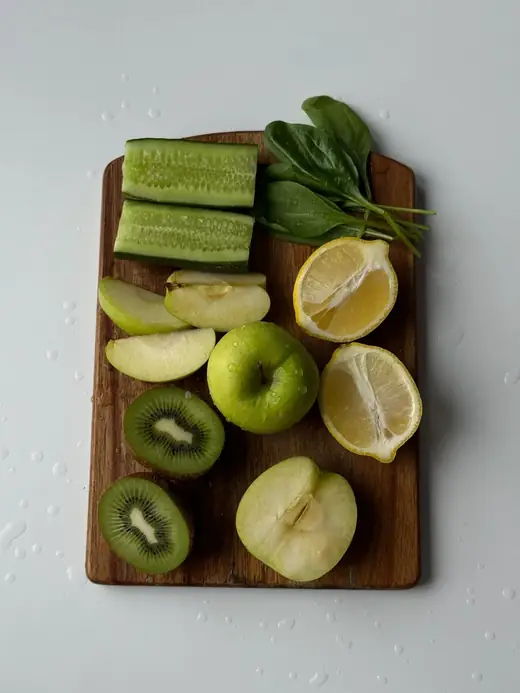 Cucumber, green apple, kiwi, lemon and spinach on a wooden board