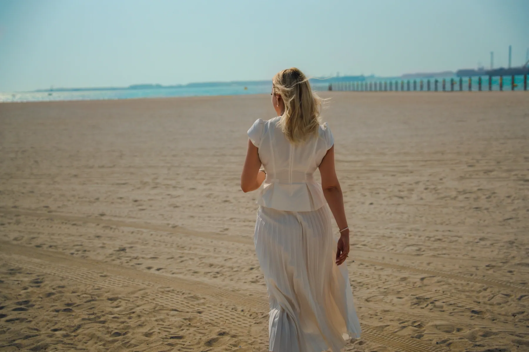 Founder walking alone on the beach in a soft white dress