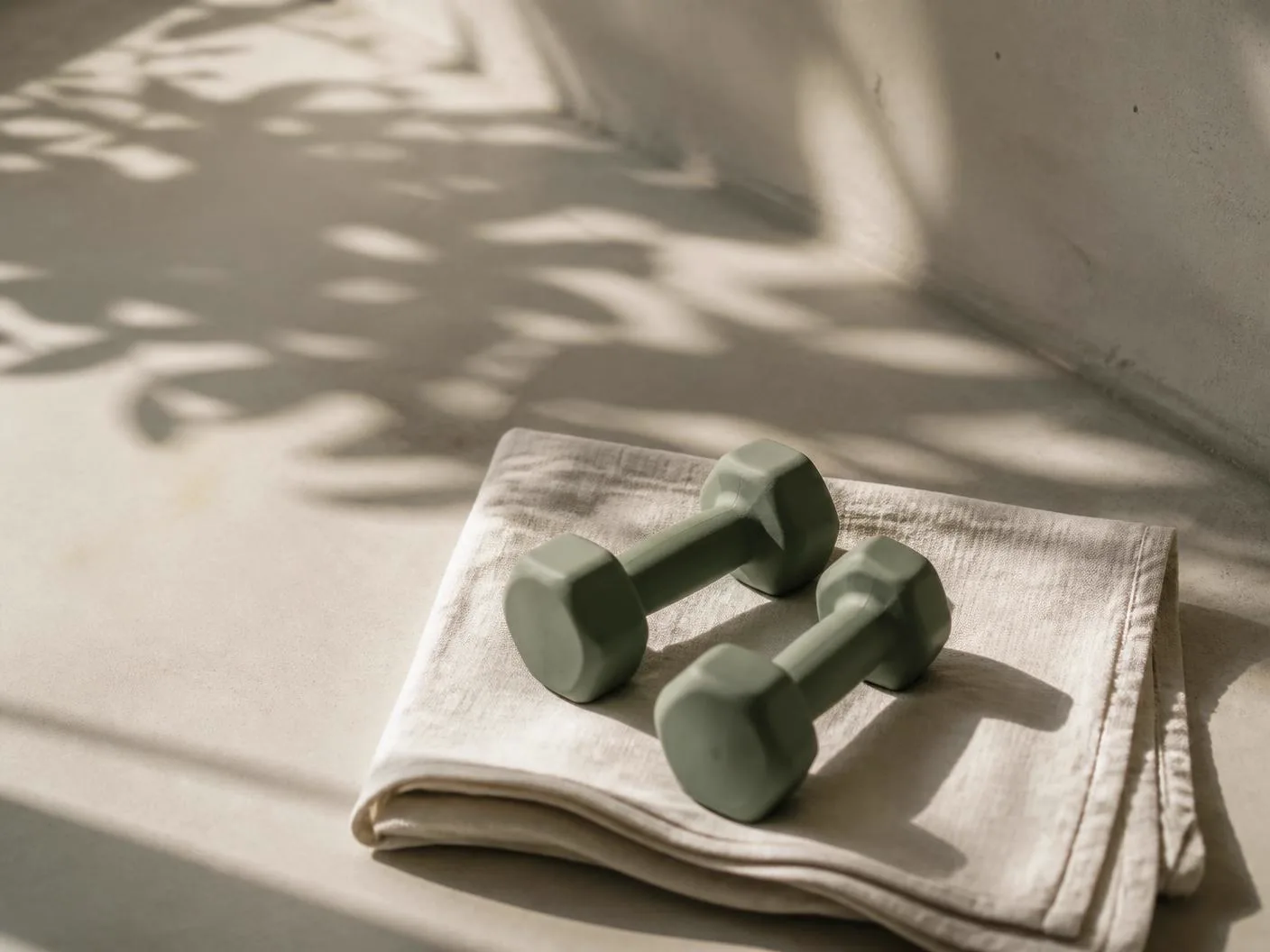 Two small dumbbells on folded linen in soft morning light